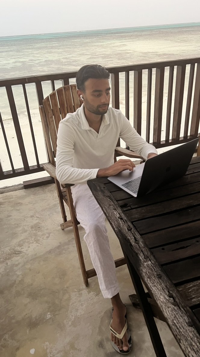 Xavier werkt op zijn laptop aan het strand